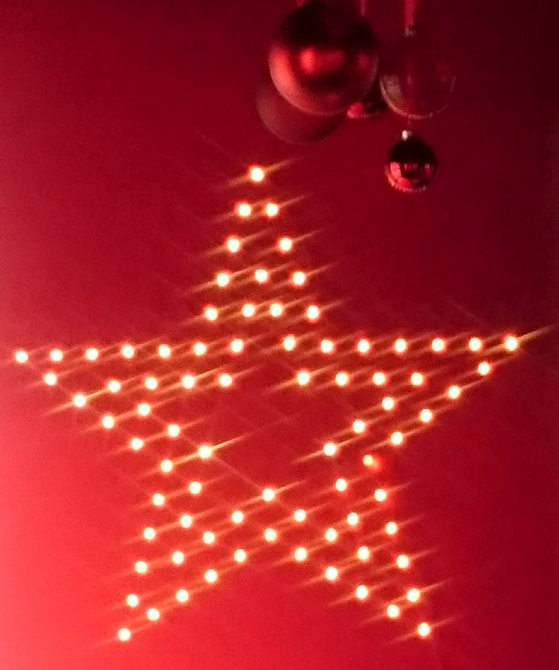 Leuchtender Stern auf rotem Grund mit Weihnachtskugeln